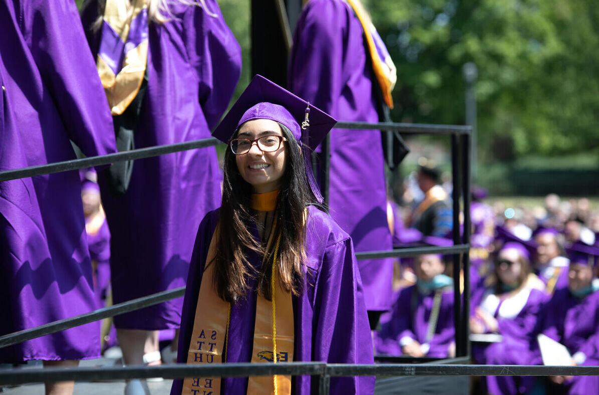 A female graduate smiles while walking up to the stage to receive her diploma